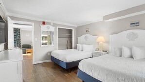 Habitación de hotel con dos camas, un armario, tocador y baño.