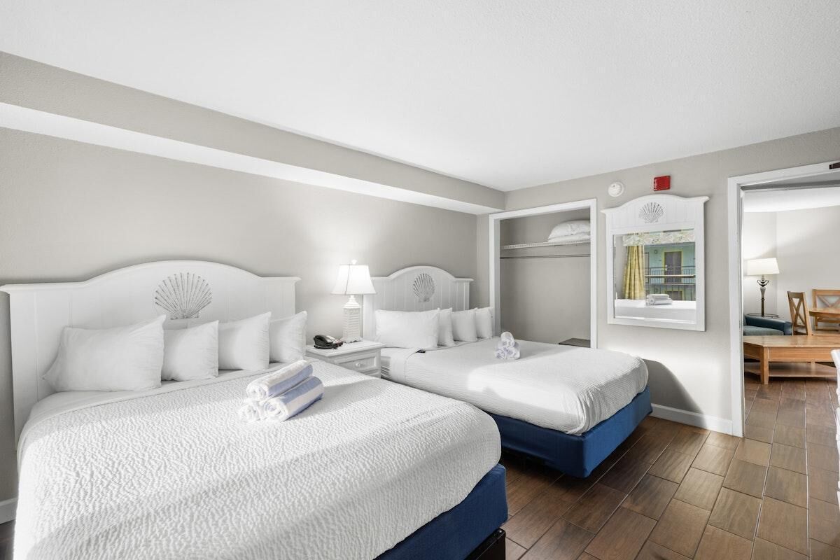 A hotel room with two beds, a wardrobe, a desk, and a window with a view.