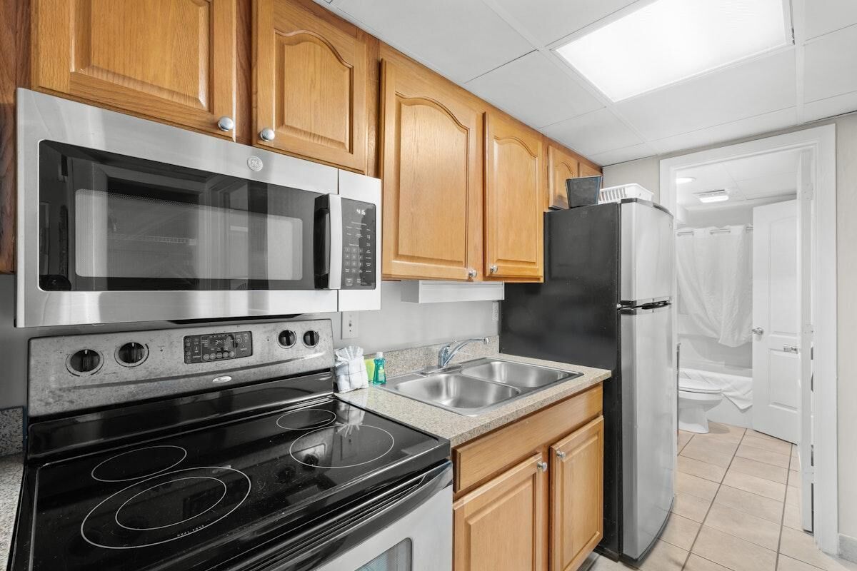 A kitchen with wooden cabinets, a stainless steel microwave, oven, and refrigerator.