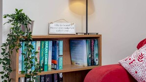 A bookshelf with books, a sign, and a lamp. - Kinnessburn Road Apartment (No 20) (St Andrews)
