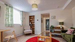 A living room with a red carpet, wooden furniture, a green sofa, and a bookshelf. - Kinnessburn Road Apartment (No 20) (St Andrews)
