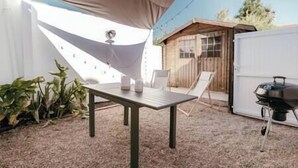 A patio with a table and chairs, a barbecue grill, and a wooden shed. - Maison 6pers 1,2km de la Plage Smarttv Fibre (Les Sables-d'Olonne)