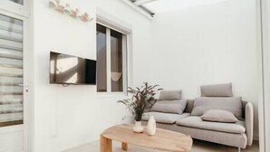 A modern living room with a sofa, a coffee table, and a TV mounted on the wall. - Maison 6pers 1,2km de la Plage Smarttv Fibre (Les Sables-d'Olonne)