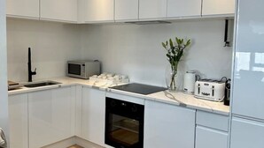 Ett modernt kök med vita skåp, en svart ugn, en mikrovågsugn och en brödrost.