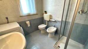 A bathroom with a bathtub, two toilets, a bidet, and a glass-enclosed shower. - Luminous Flat With Balcony (Caorle)