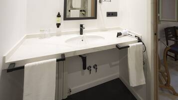 Un baño moderno con un lavamanos blanco, un espejo y un perchero para toallas.