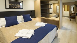 Una cama bien hecha con ropa de cama azul y blanca, una mesita de noche y una estantería en la pared.