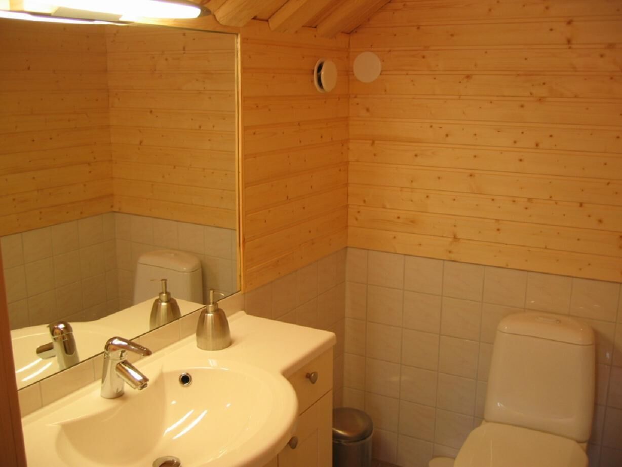 A wooden-paneled bathroom with a sink, mirror, and toilet.
