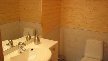 A wooden-paneled bathroom with a sink, mirror, and toilet.