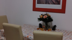 A dining area with a table set for four, a framed painting on the wall, and a vase with flowers on the table. - Gemütliches 2-zimmer Appartement im Herzen von Lahnstein (Lahnstein)