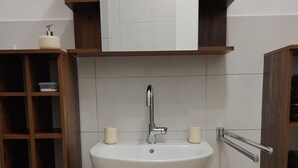 A bathroom with a white sink, wooden cabinets, and a mirror above the sink. - Gemütliches 2-zimmer Appartement im Herzen von Lahnstein (Lahnstein)
