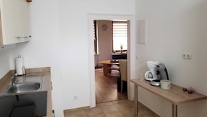 A compact kitchen with a sink, a coffee maker, and a dining area with a table and chairs. - Gemütliches 2-zimmer Appartement im Herzen von Lahnstein (Lahnstein)