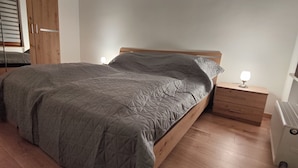 A bedroom with a wooden bed, a nightstand with a lamp, a radiator, and a wardrobe. - Gemütliches 2-zimmer Appartement im Herzen von Lahnstein (Lahnstein)