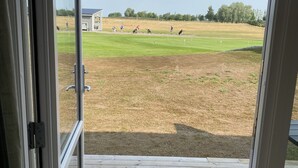 Blick von einem Zimmer mit einer Holzterrasse auf einen Golfplatz.