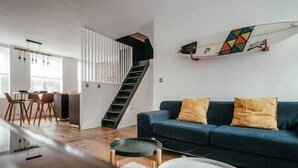 A modern living room with a blue sofa, wooden floor, and a staircase leading to another level. - Duplex 4pers - 100m du Métro - Smarttv - Fibre (Lille)