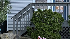 Une maison avec un escalier en bois, un mur en pierre et une variété de fleurs aux couleurs vives dans le jardin.