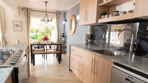 A modern kitchen with wooden cabinets, a marble countertop, and a built-in dishwasher. - Stylish, light villa w/pool. All modern amenities, gated. Right by the beach. (Rodney Bay)