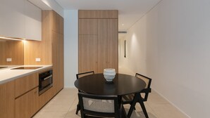A modern kitchen with wooden cabinets, a black dining table, and a stone bowl centerpiece. - City Living at it's Finest (Sydney)