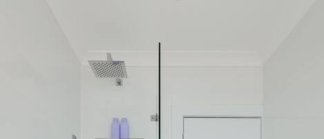 A modern bathroom with a white bathtub, a showerhead, and a door.