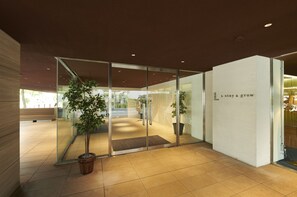 A modern interior with glass doors, a wooden bench, and potted plants. - L stay & grow HARUMI (Tokyo)