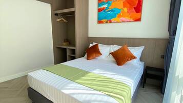 A hotel room with a bed, a wardrobe, and a colorful abstract painting on the wall.