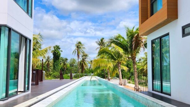 A modern hotel with a swimming pool, large windows, and palm trees. - Sand Dance Hotel (Prachuap Khiri Khan)