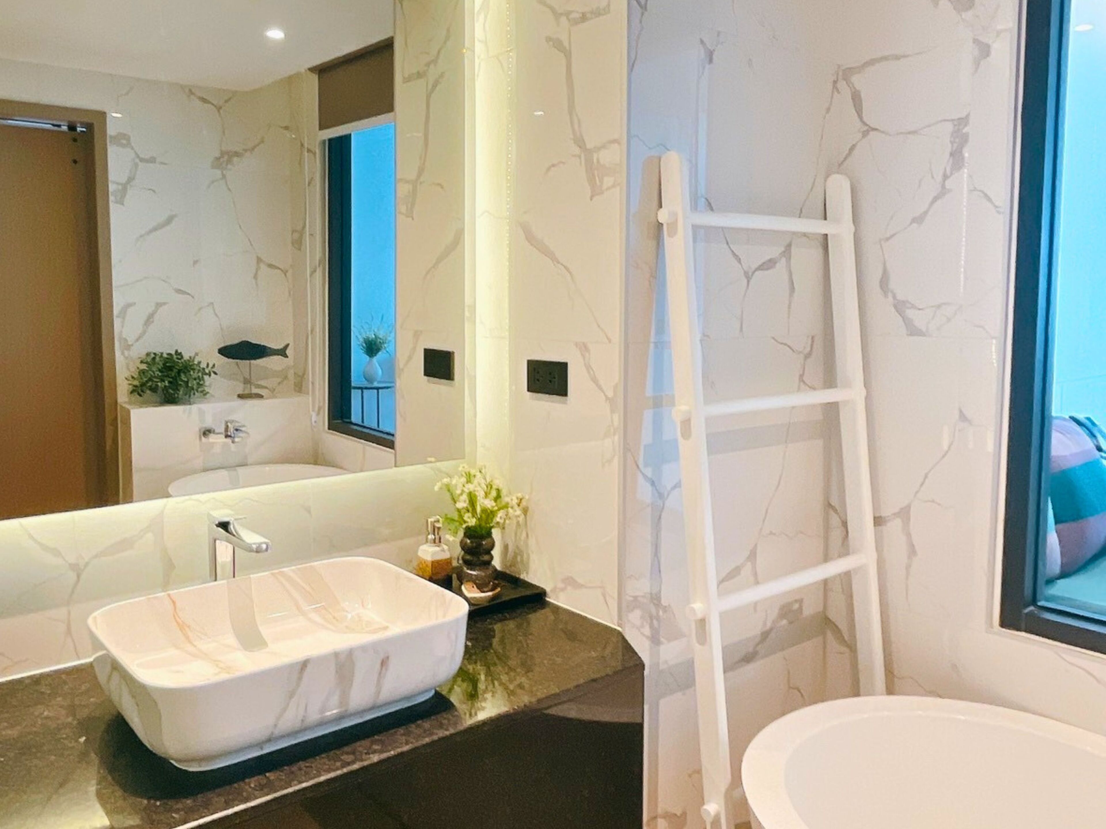 Un baño moderno con una bañera independiente, un espejo grande y un ventanal con vistas.