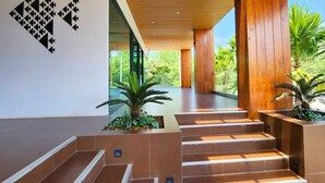 A modern interior with a staircase leading to a balcony, wooden paneling, and a geometric wall art piece. - Sand Dance Hotel (Prachuap Khiri Khan)