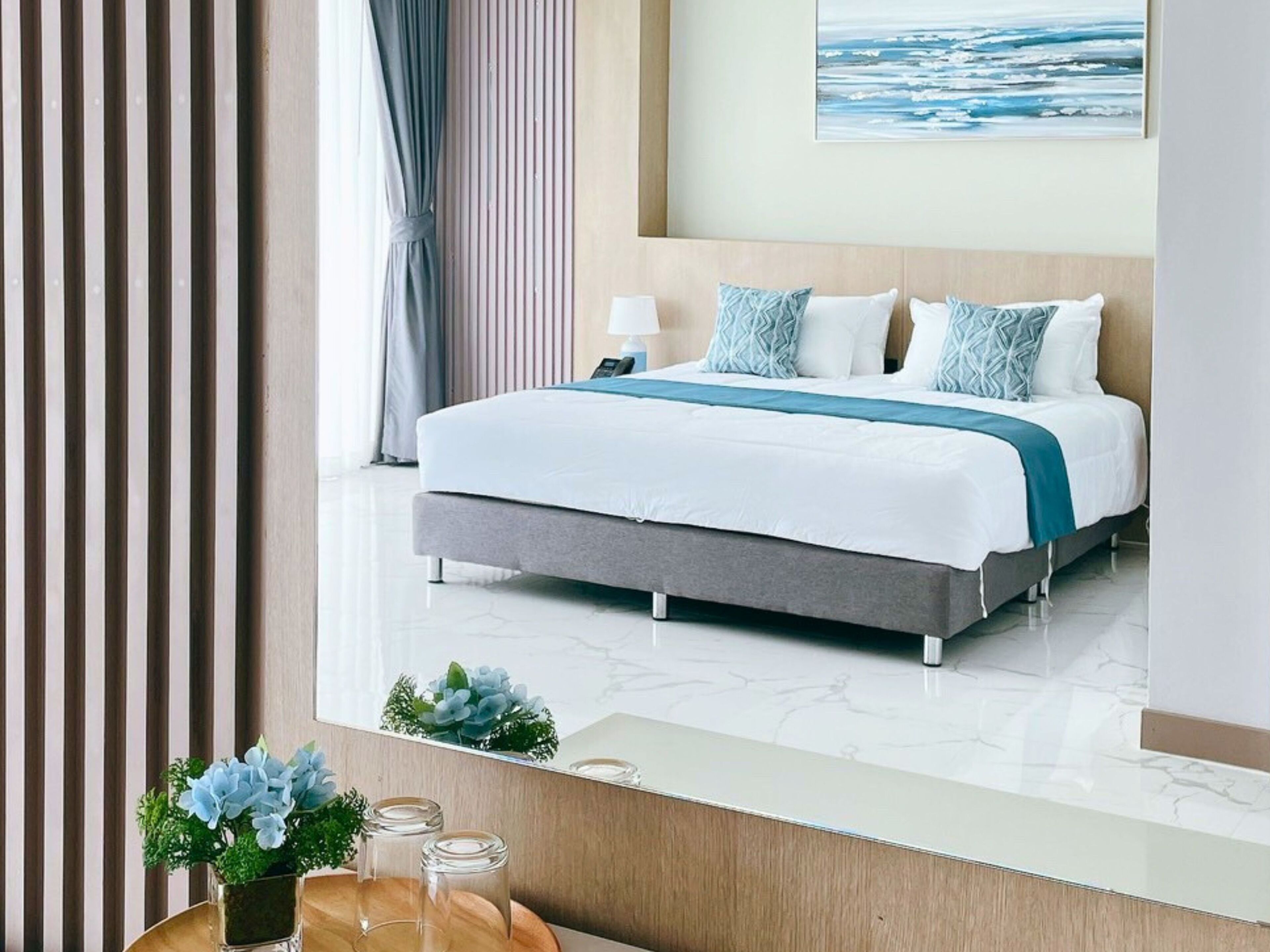 Una moderna camera d'albergo con un letto grande, un comodino, uno specchio e vista sull'oceano.