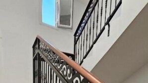 Una escalera con barandilla de hierro negro y pasamanos de madera.