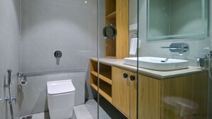 Une salle de bain moderne avec une douche à parois de verre, des toilettes blanches, un meuble-lavabo en bois et un grand miroir.