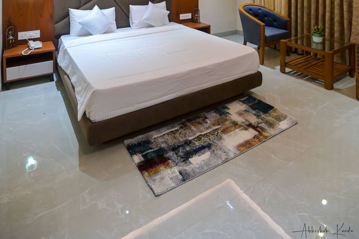 A modern hotel room with a large bed, a desk, a chair, and a ceiling fan.