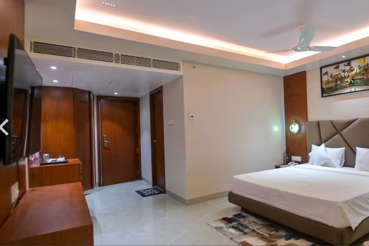 A modern hotel room with a large bed, a desk, a wardrobe, and a ceiling fan.