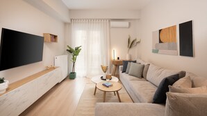 Uma sala de estar moderna com uma televisão de tela plana, um sofá, uma mesa de centro e um vaso de planta.