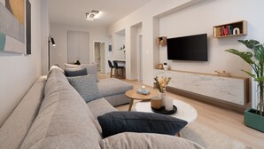 Uma sala de estar moderna com um sofá, mesa de centro e uma TV de tela plana fixada na parede.