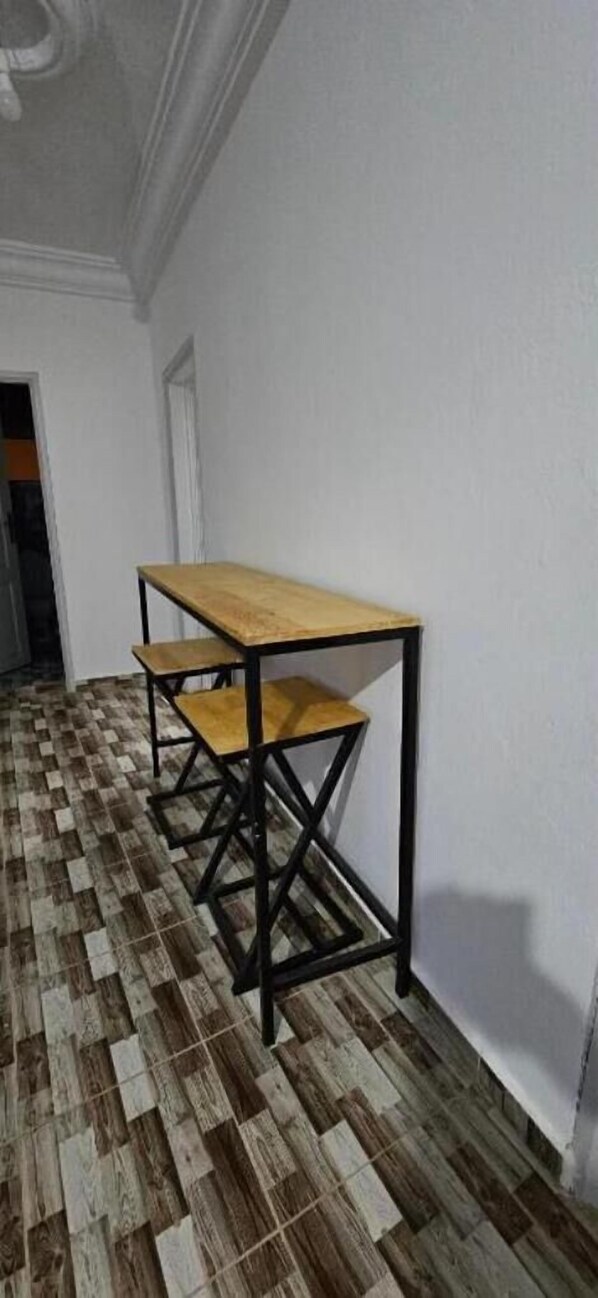 Un pasillo con piso de madera y una mesa con estructura de metal negro.