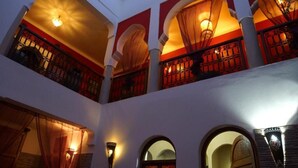 Interior com vários níveis, varandas em arco, iluminação acolhedora e arandelas decorativas.