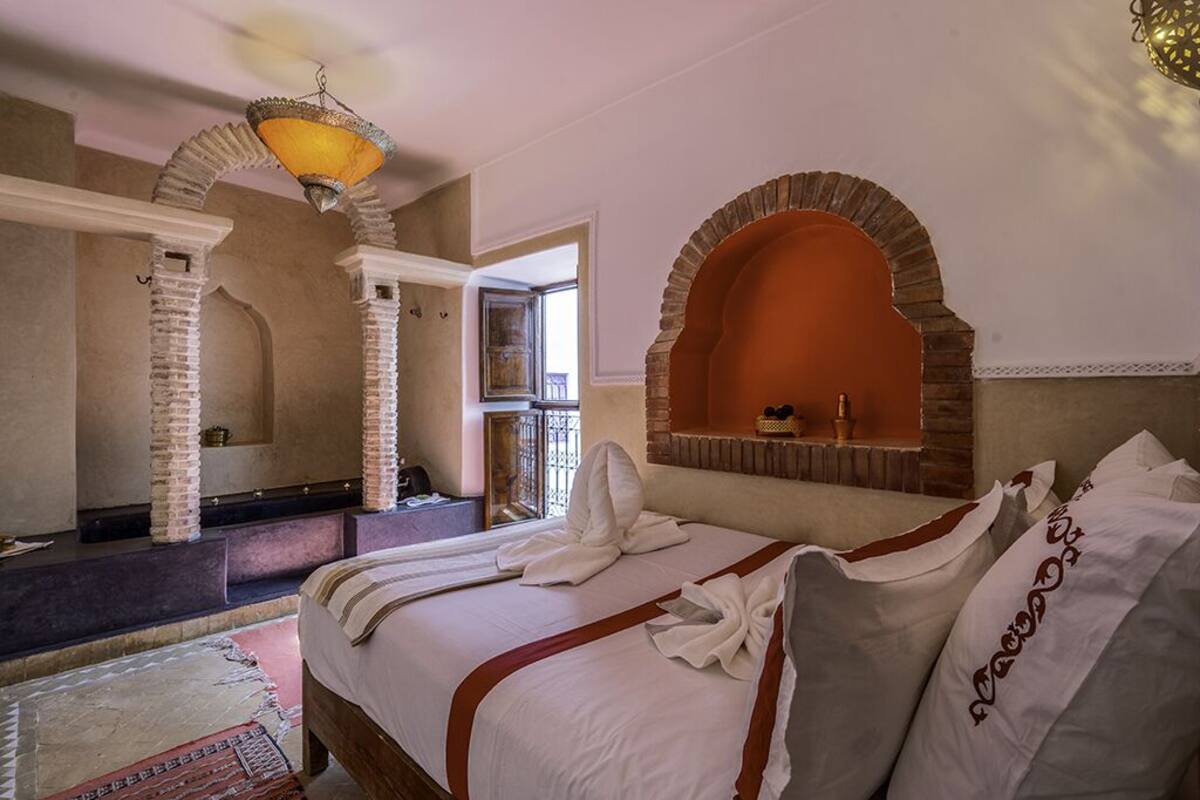 A hotel room with a large bed, a small sitting area, and a view of the outside.