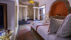 Quarto com cama, janela, espelho e arco decorativo.