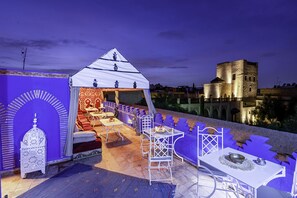 An outdoor seating area with a white tent, tables, and chairs, overlooking a historic building.