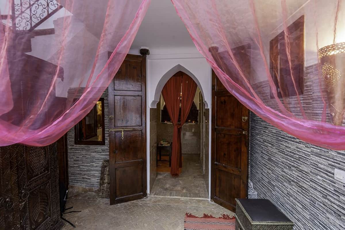 A room with a wooden door, a small table, and a bench.