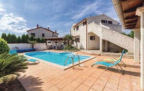A pool area with a clear blue pool, two lounge chairs, and a stone staircase leading to a building. - Holiday apartment with air conditioning (Banjole)
