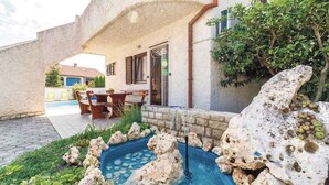Un edificio in pietra con patio, una piccola piscina con rocce e un tavolo con sedie.