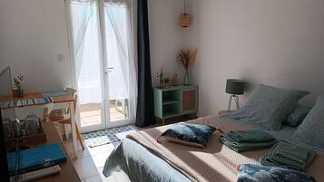 A bedroom with a bed, a desk, and a chair. There is a sliding glass door leading to an outdoor area.