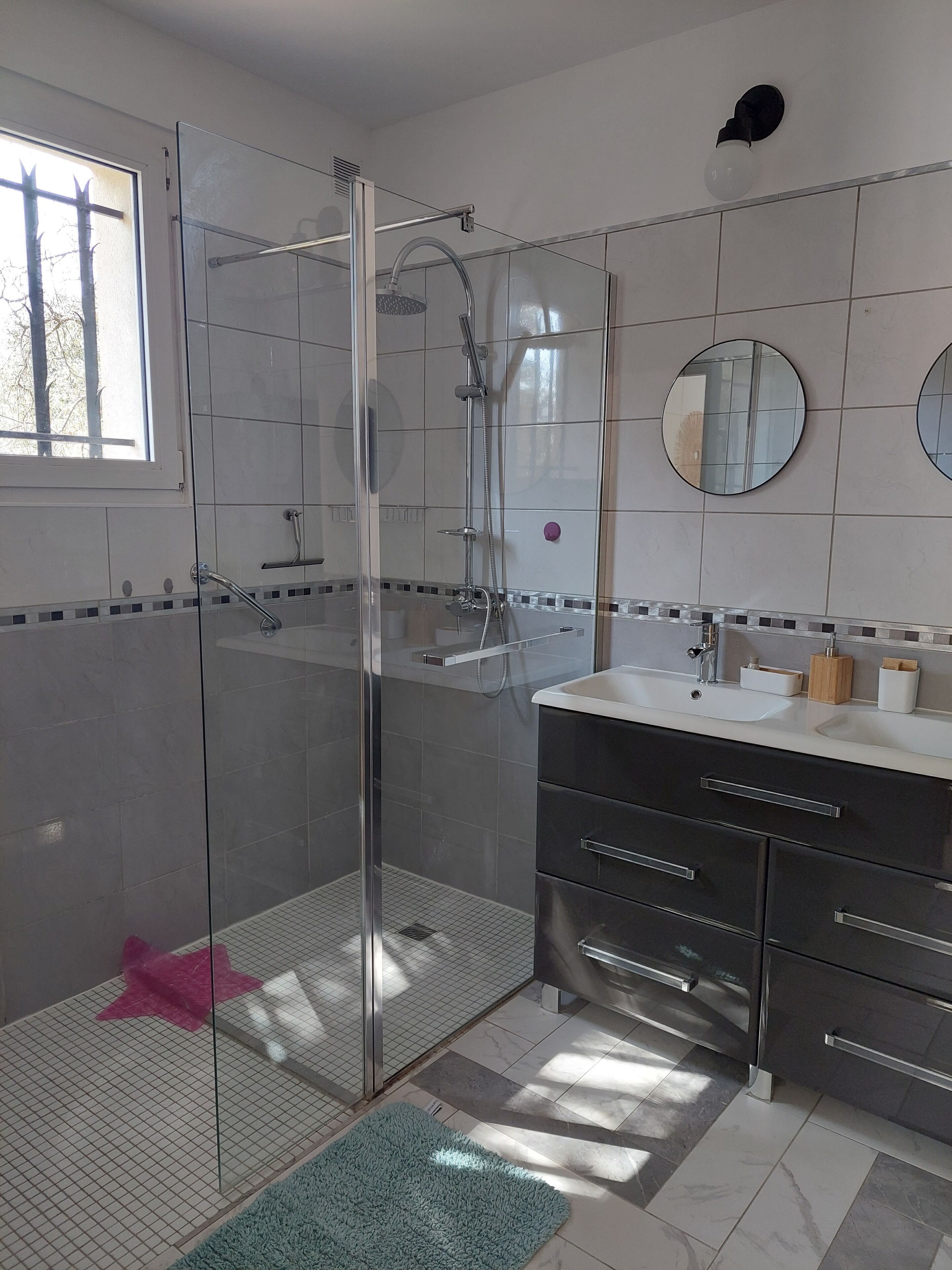 A modern bathroom with a glass-enclosed shower, a vanity with a sink, and a mirror.