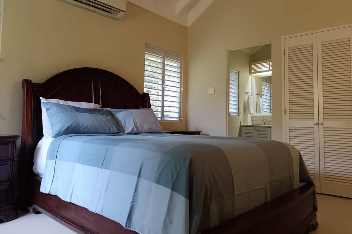 A bedroom with a bed, a nightstand, a dresser, a mirror, and a closet.