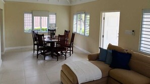 Amplia sala de estar con mesa y sillas de comedor, un sofá y un ventilador de techo.