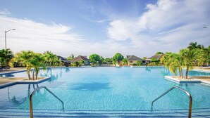 Una gran piscina al aire libre rodeada de palmeras y casas.