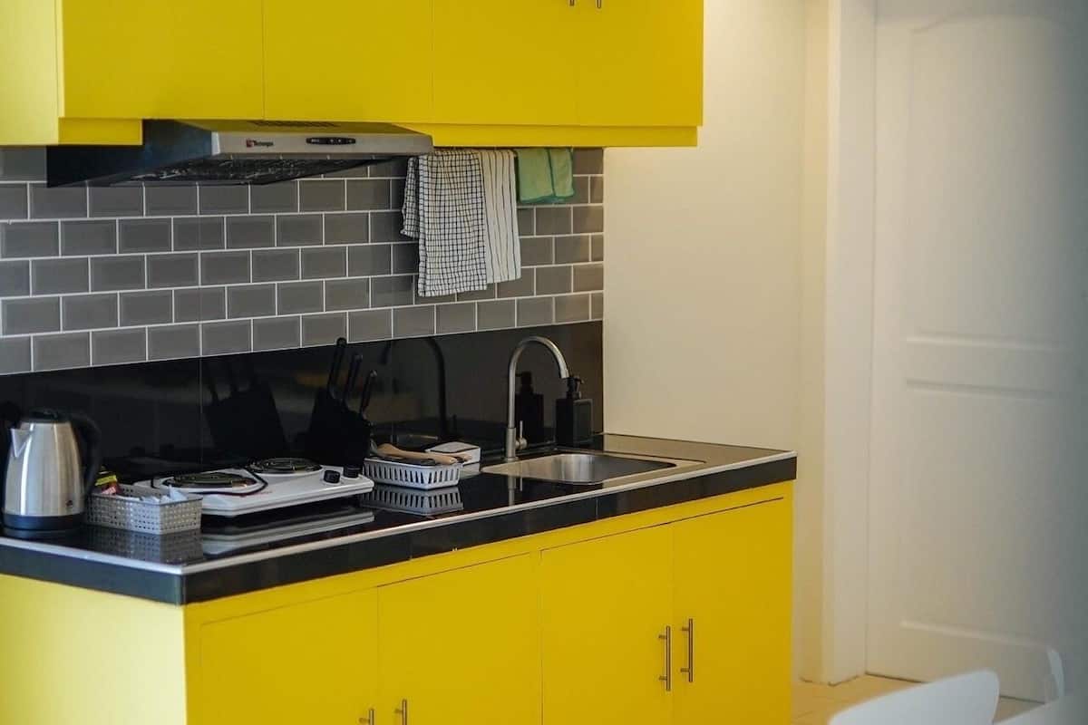 A kitchen with yellow cabinets, a black countertop, and a white dining table with chairs.