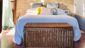 A bedroom with a brick wall, a bed with white bedding, a wicker bench, and a hanging light fixture. - Ephemeral - Relaxing Retreat (Abruzzo)